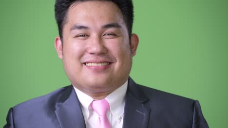 joven apuesto hombre de negocios asiático con sobrepeso contra un fondo verde