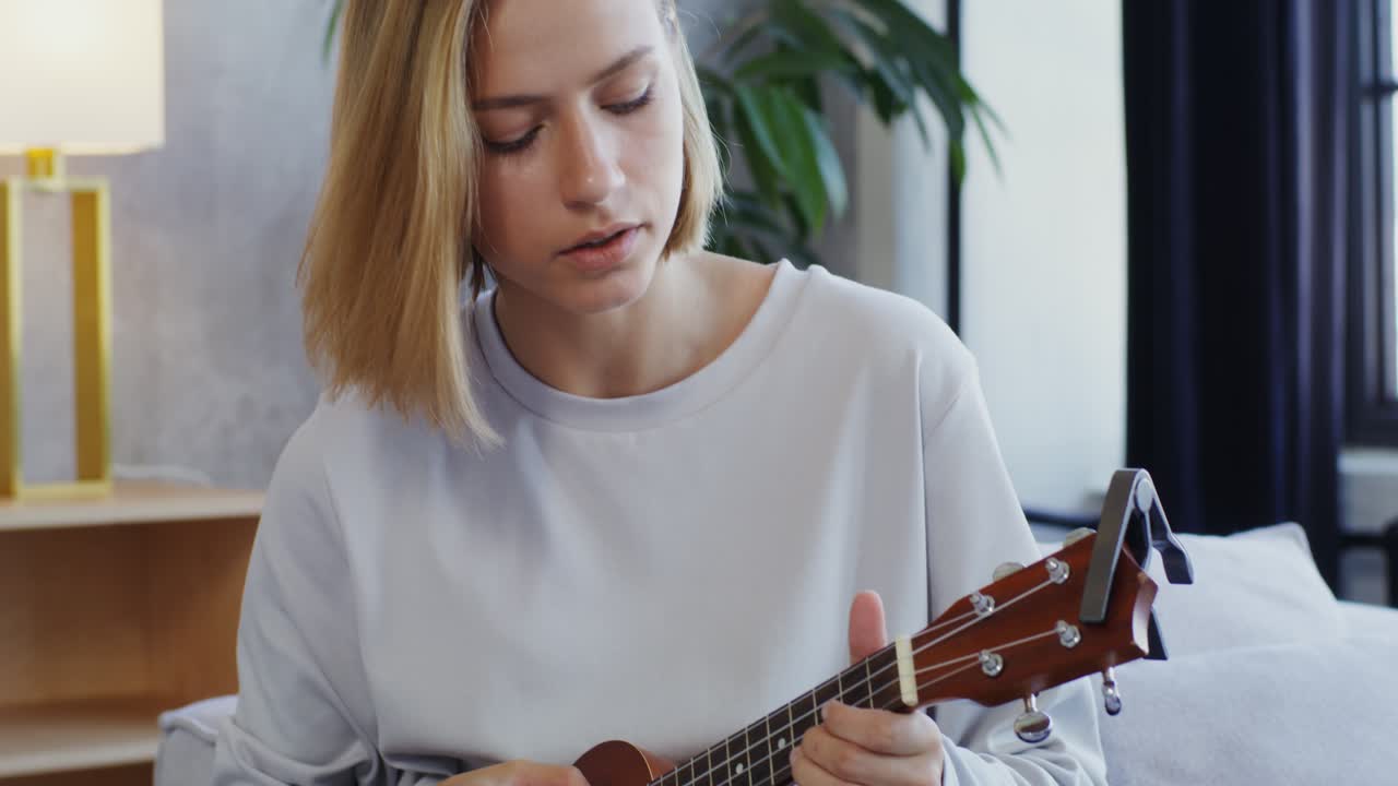 mujer tocando el ukulele en casa