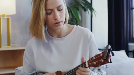 woman playing ukulele at home