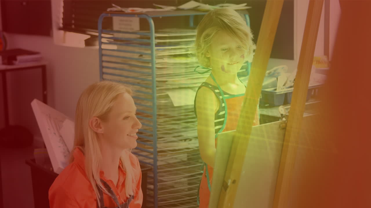 puntos de luz contra la maestra caucásica que enseña a una niña a pintar en la escuela primaria