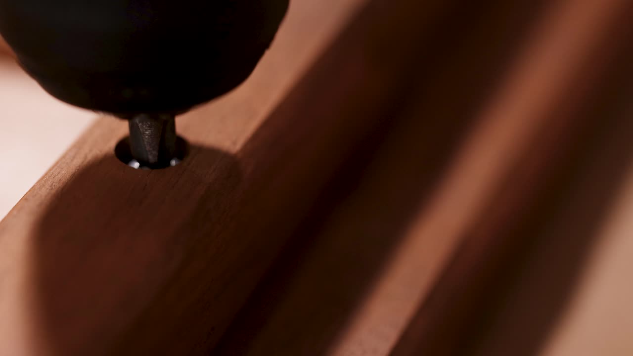 Close-up of a screw being driven into wood using an electric drill, highlighting precision and craftsmanship