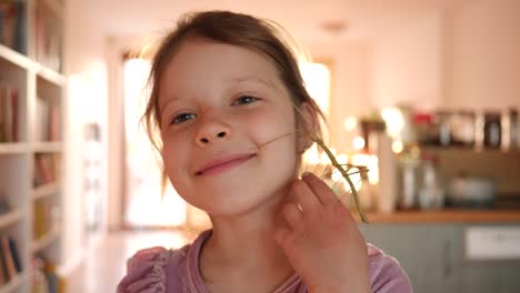 el retrato de una niña linda sostiene una mascota de insecto en las manos y se la pone en la cara en casa divertirse y sonreír