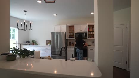 Mujer-Joven-Está-Lavando-Y-Guardando-Platos-En-La-Cocina-En-Una-Tarde-Soleada,-Tareas-Domésticas