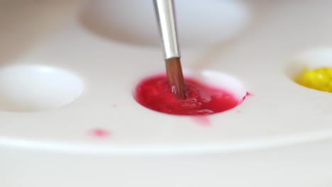 mixing red paint on a palette