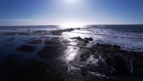 drone fly over rock formations and tide pools at mavericks beach, california during sunset