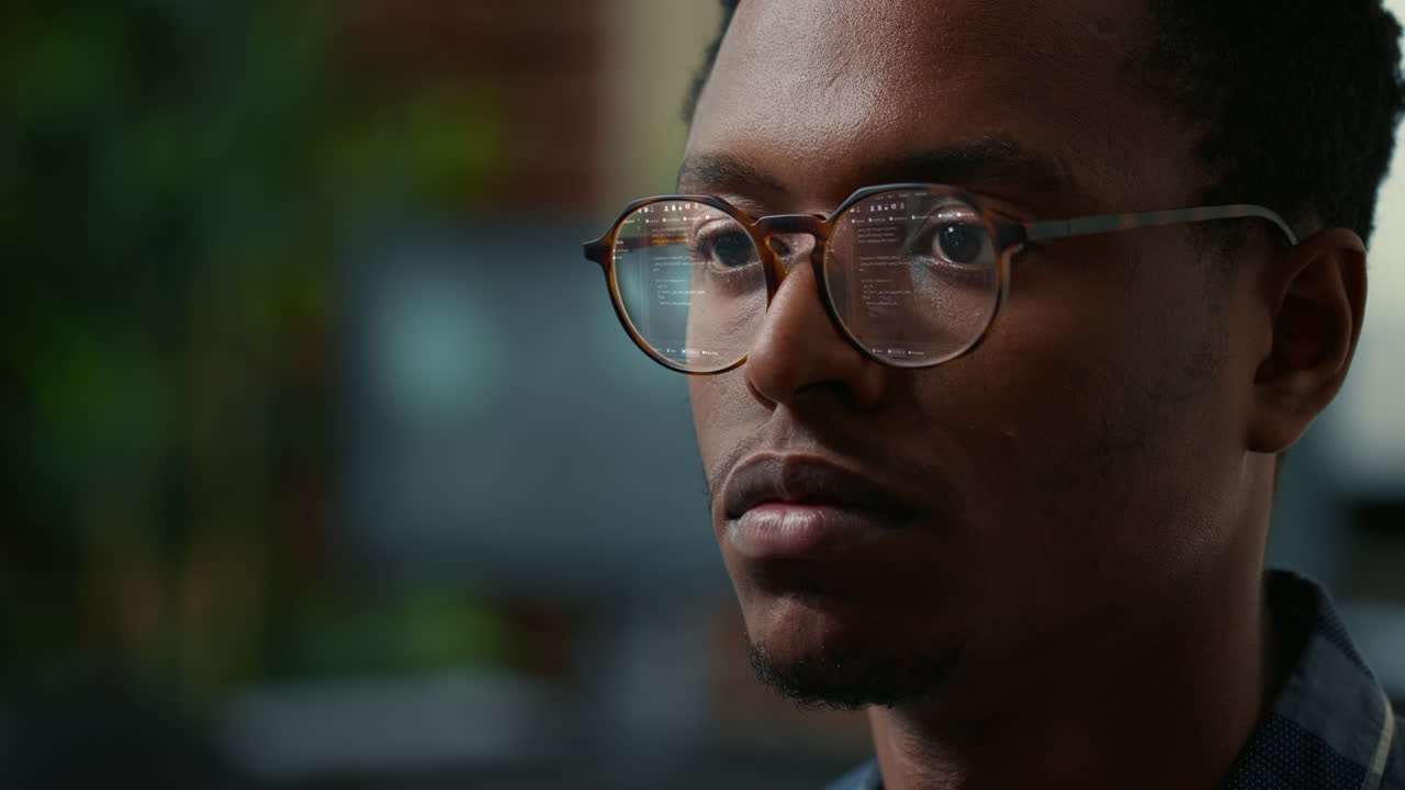 Portrait of software developer with vfx of running code reflected in glasses reading algorithm