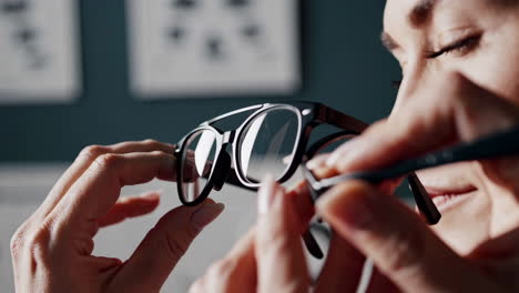 close-up of a person's hands adjusting or examining a pair of eyeglasses