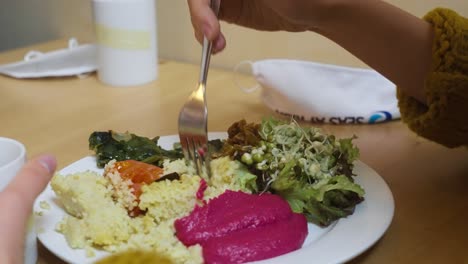 slow motion shot of a woman using her fork and eating her lunch