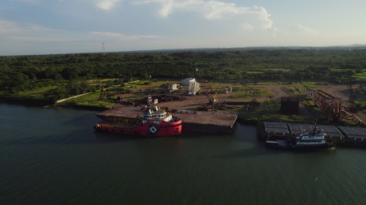 해가 지는 동안 강 근처 에 있는 조선소 에서 화물 을 풀고 있는  ⁇ 커