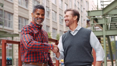 two middle aged male work colleagues outside their workplace