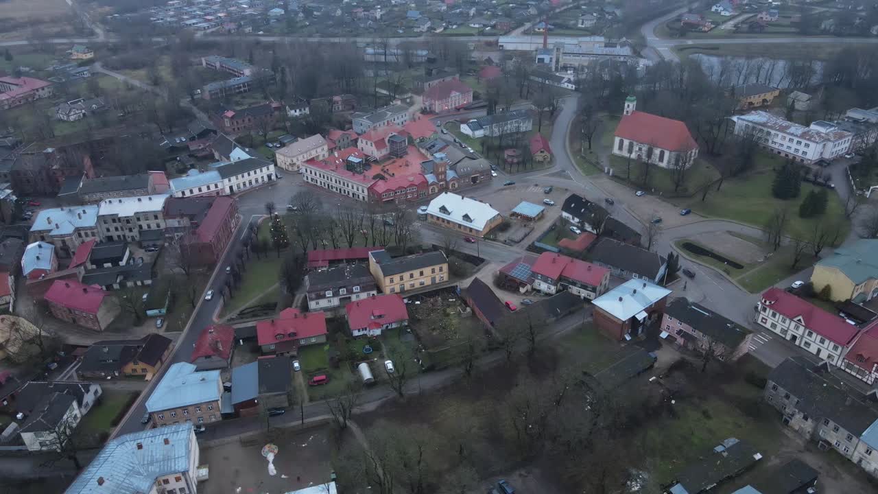 Aerial perspective of Limbazi city showcasing colorful rooftops, historical buildings, a church, and surrounding greenery. A serene, small-town charm is evident in this view.
