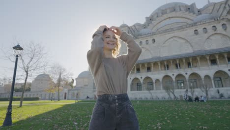 beautiful woman posing on background of temple. action. happy woman dances outside mosque on sunny day. beautiful woman circling near mosque on background of sun rays