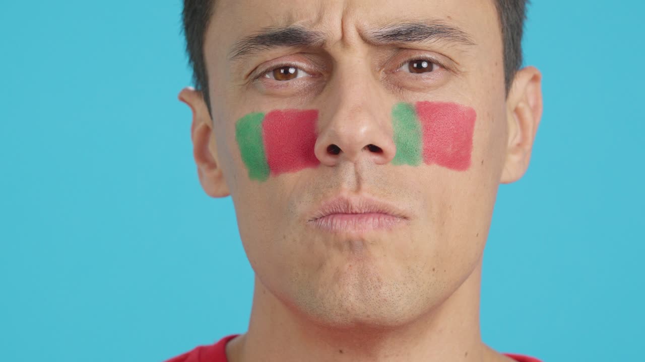 Serious man with a portuguese flag painted on the face