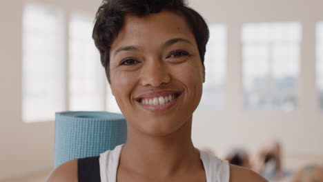 Retrato-Hermosa-Mujer-De-Yoga-De-Raza-Mixta-Sonriendo-Con-Confianza-Disfrutando-De-Un-Estilo-De-Vida-Saludable-Con-Gente-Practicando-En-El-Fondo-Del-Gimnasio