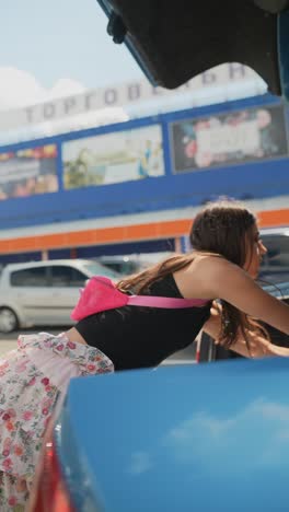 teenage girl opening car trunk