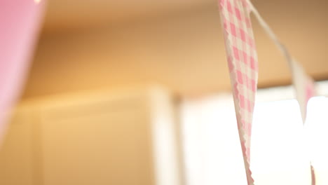 Handheld-Footage-of-Pink-Checkered-Flag-Banner-in-Warmly-Lit-Room