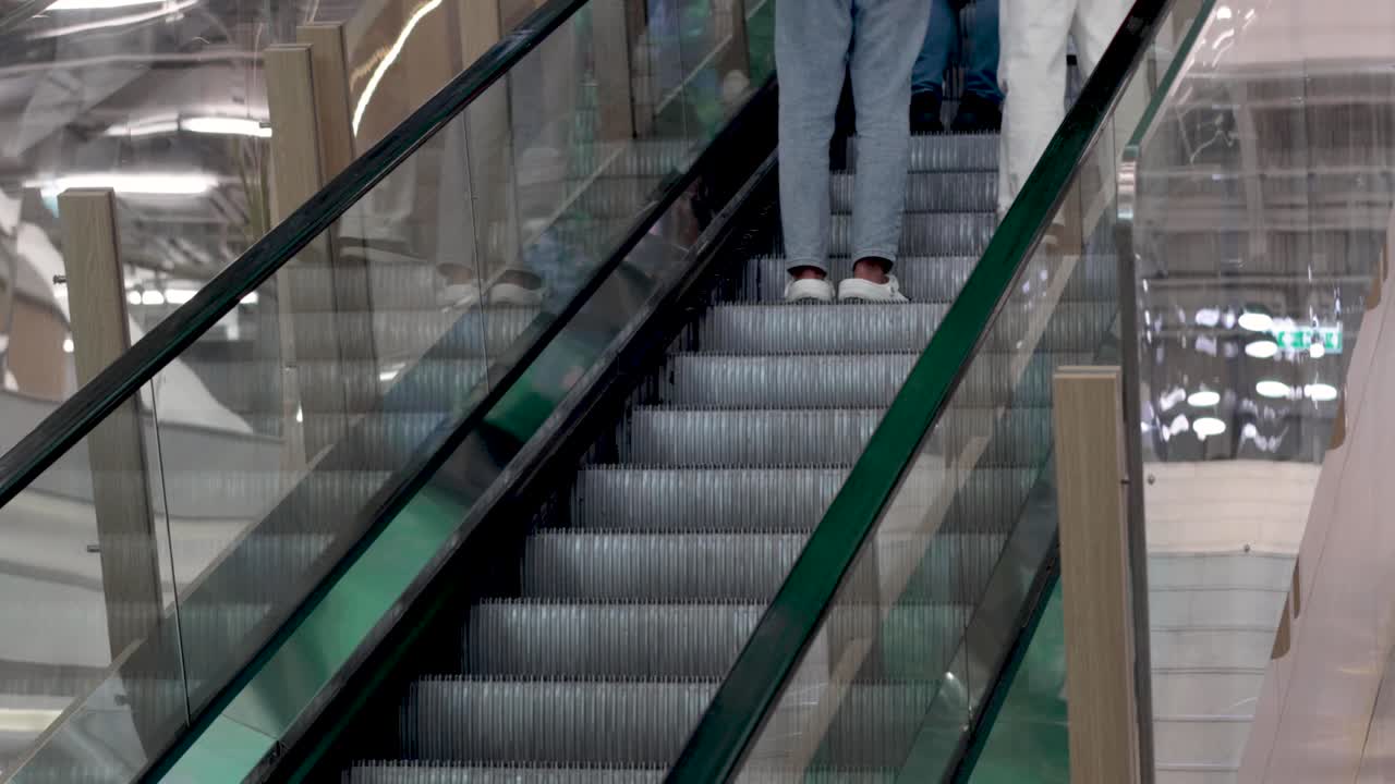 건물 에 있는 에스컬레이터 를 타고 올라가는 두 사람