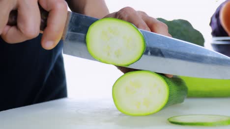 4k mujeres cortando a mano calabacín fresco en la tabla de cortar. la mano femenina corta el pepino japonés crudo en círculos con un cuchillo en la tablas de corte. concepto de alimentos saludables. técnicas de movimiento de la cámara.
