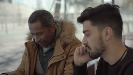 multiracial men discussing work in cafe