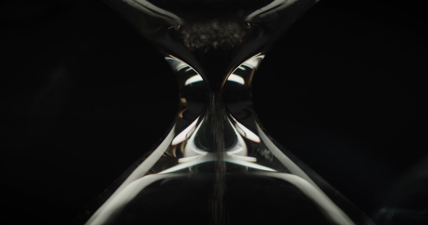 Macro shot of sand pouring in hourglass