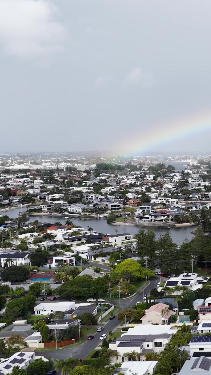 Ampia ripresa aerea di un arcobaleno che si estende su un quartiere residenziale con canali.