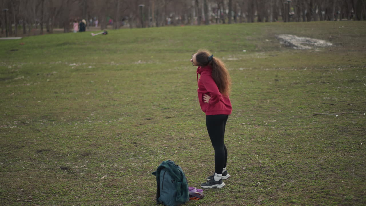 Woman In Park Preparing For Running Exercise, Female Athlete Adjusting Clothing Before Jogging In Park, Individual In Park Preparing Gear And Adjusting Clothing For Exercise Session