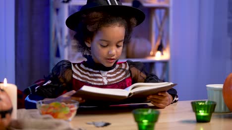 young witch reading a book on halloween night