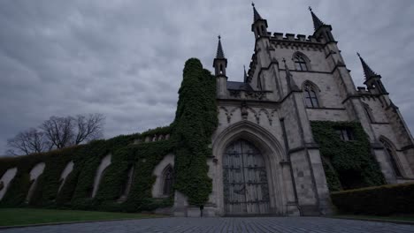 imposing gothic castle, draped in lush ivy, rises dramatically against a backdrop of swirling clouds, evoking a sense of mystery and enchantment in the twilight atmosphere