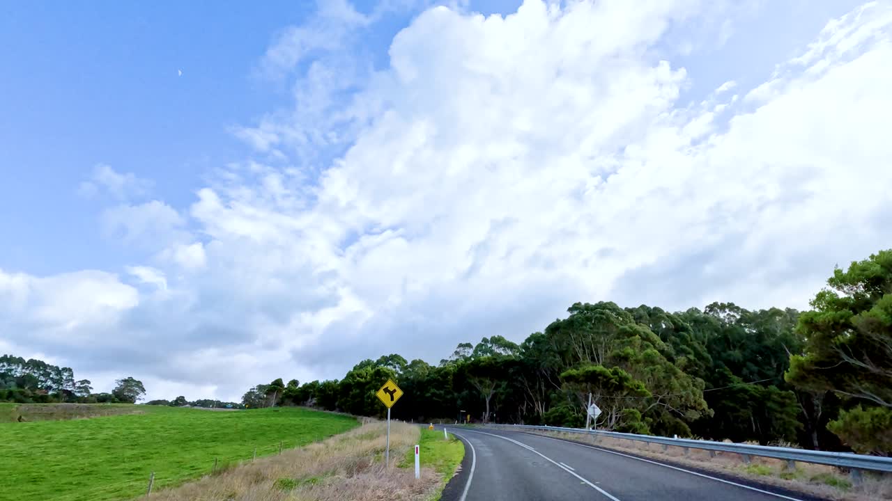 푸른 하늘 아래 울창한 풍경과 휘어지는 도로를 가로질러 자연의 아름다움의 본질을 포착하는 조용한 드라이브