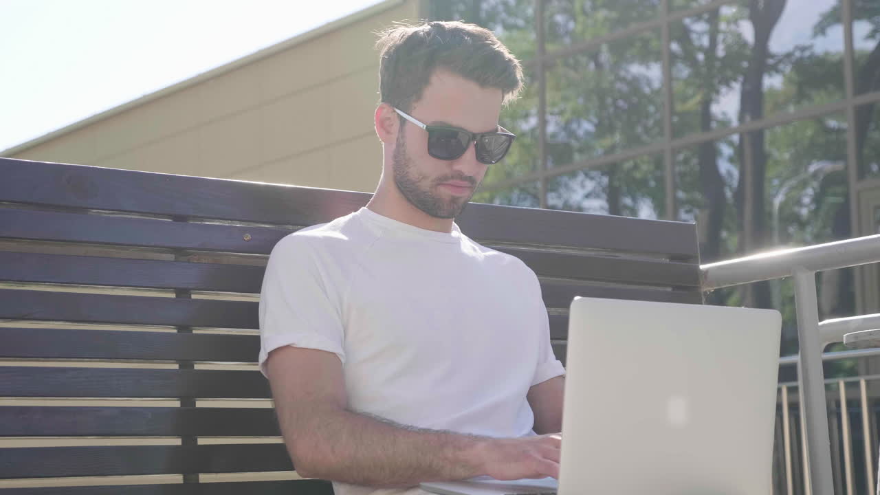hombre trabajando en una computadora portátil en un banco al aire libre