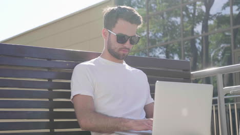 man working on laptop on outdoor bench