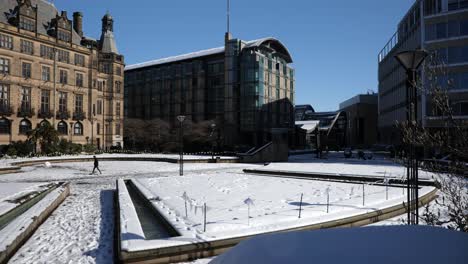 People-walking-through-snowy-Sheffield-peace-gardens-on-a-sunny-day