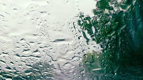 fuertes lluvias sobre el parabrisas mientras se conduce por la carretera con árboles en el fondo y limpiaparabrisas quitando las gotas de lluvia