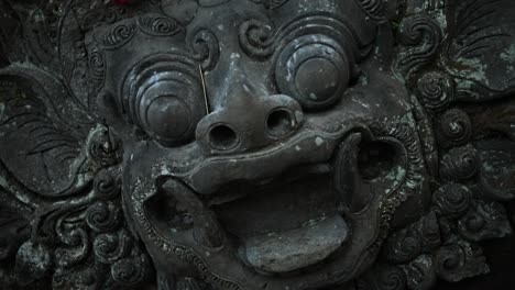 handgehaltene zeitlupenaufnahme, die sich langsam in richtung einer alten affenstatue im heiligen affenwald in bali, indonesien, dreht