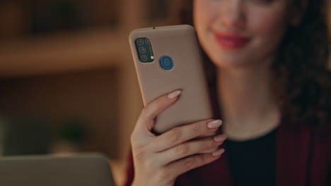positive businesswoman looking smartphone reading message evening office closeup