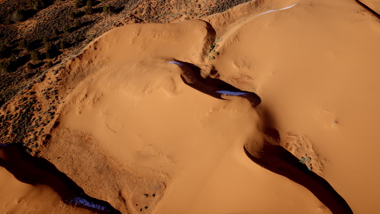 From above, a drone captures the vivid pink sand dunes and their fascinating natural designs in southern Utah.