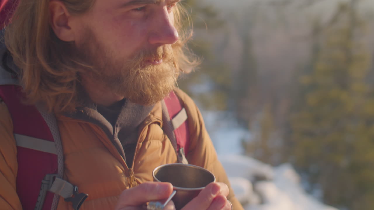 Male Tourist Drinking Hot Tea during Winter Hike in Mountains