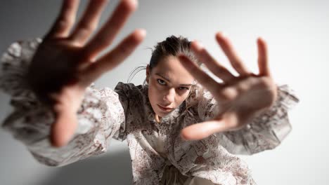 young woman reaching out with hands in slow motion on white background