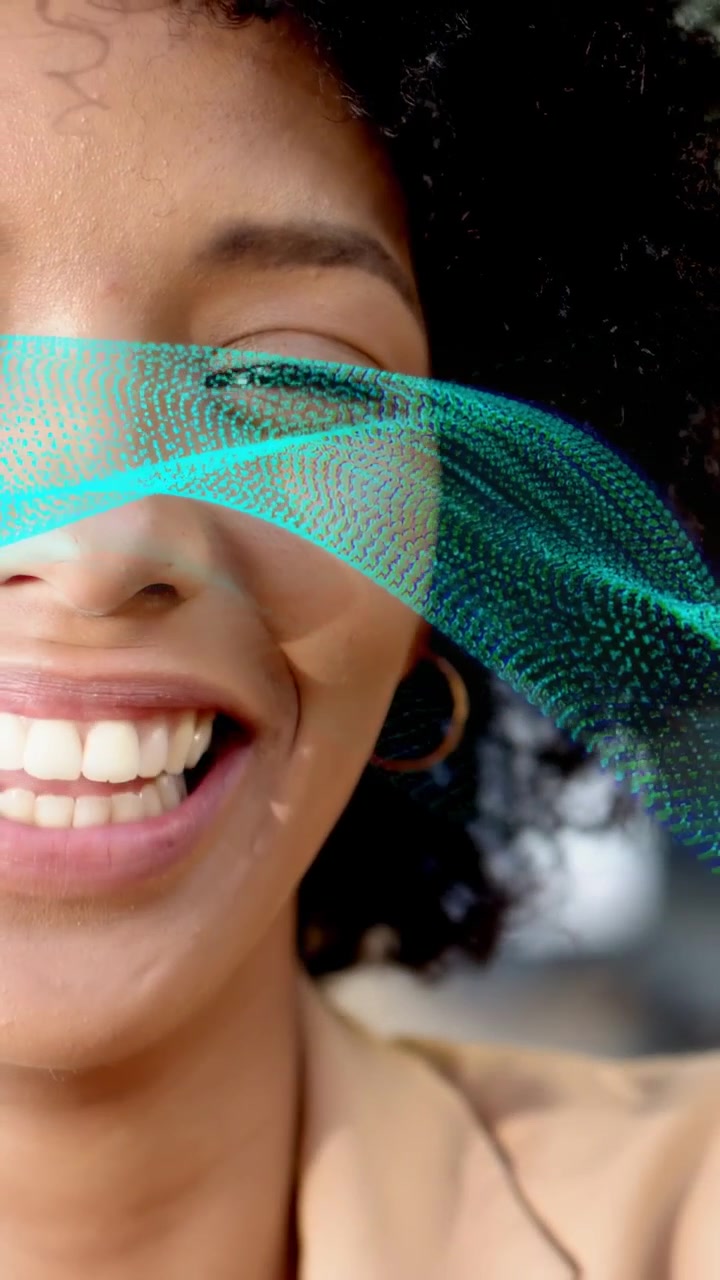 Video verticale: Donna di fronte alla telecamera, un nastro color verde acqua che entra da sinistra facendo trasformare un sorriso in una risata per la tecnologia.