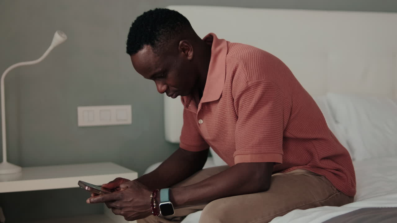 Focused Man Using Mobile Phone While Sitting on Bed