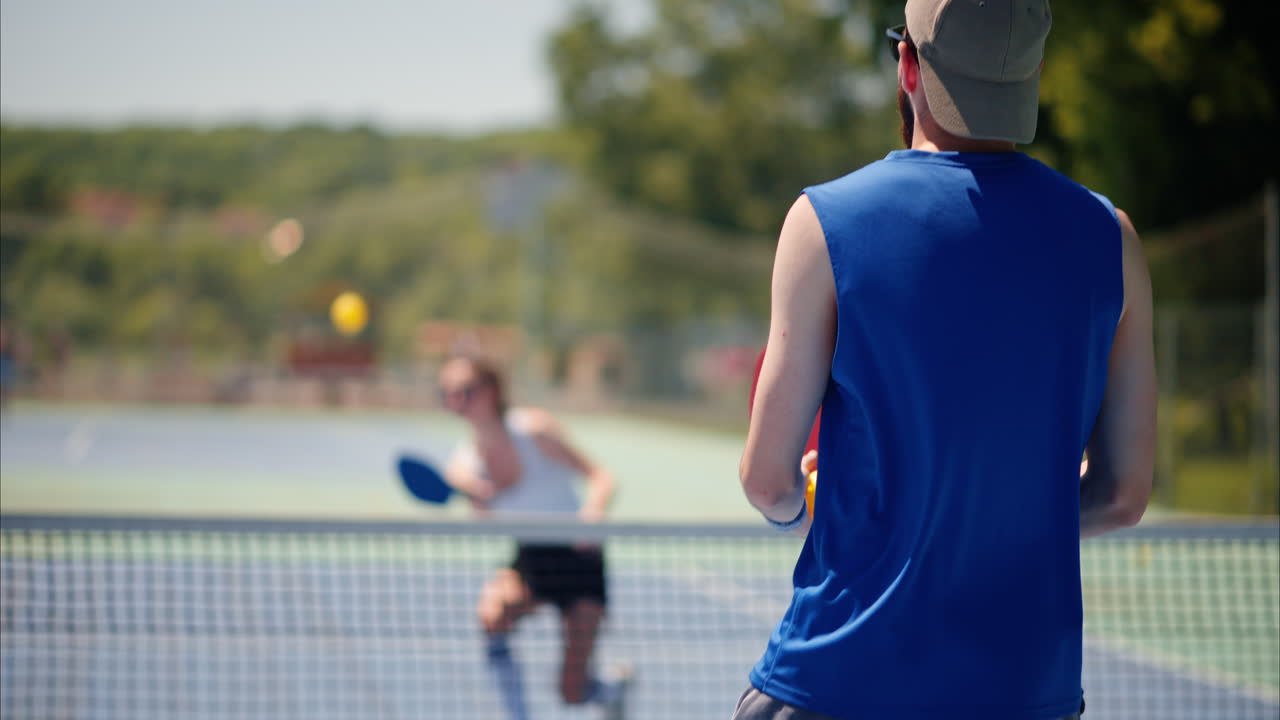 A man and a woman playing pickleball on a sunny day