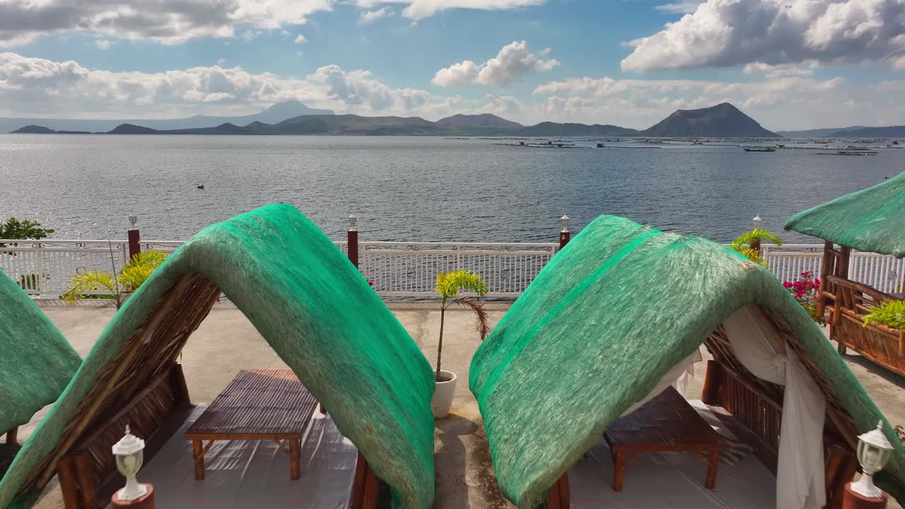 Flight through restaurant with parking asian boats at shore at Taal Lake. Mountains and fishing farm. drone forward shot.