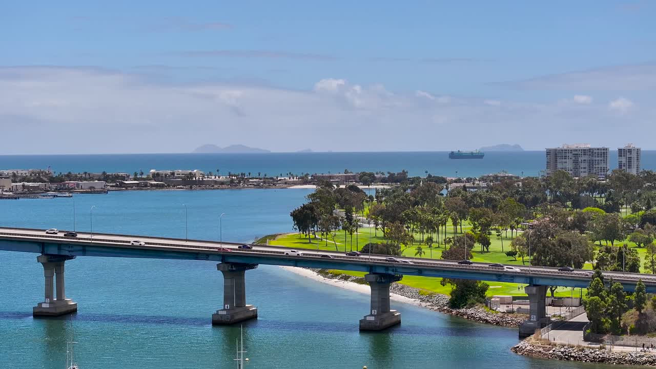 Stationary aerial view of cars driving on Coronado Bridge with the Mexican Coronado Islands in the background
