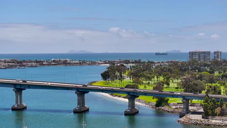 stationary aerial view of cars driving on coronado bridge with the mexican coronado islands in the background