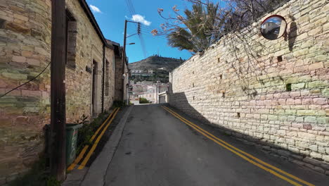 narrow uphill street in lefkara lined with stone walls and houses