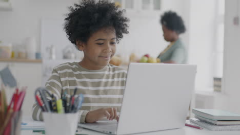 girl doing homework on laptop in a kitchen