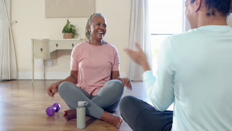 senior woman sitting on floor, smiling and holding water bottle during exercise