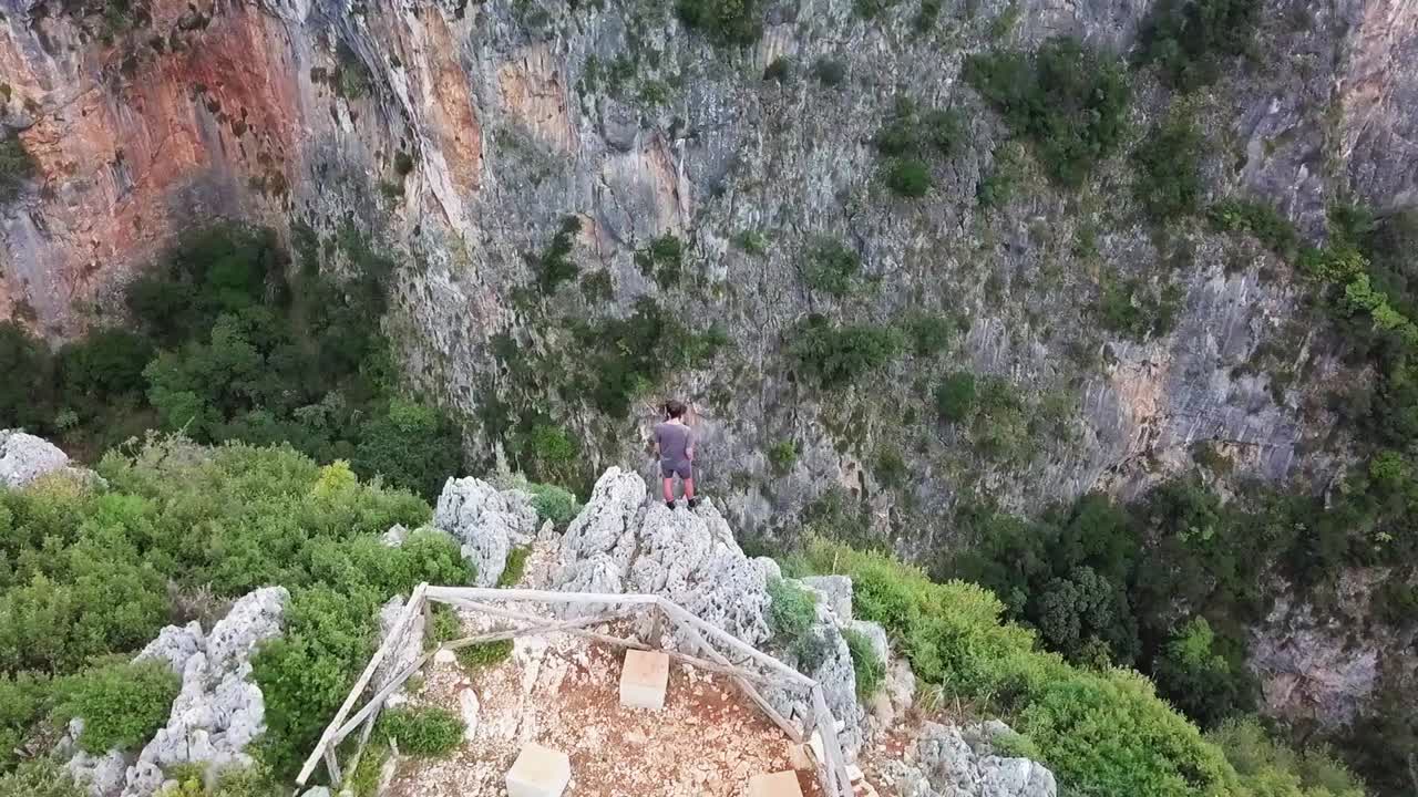 humano de pie en el borde de un acantilado mirando hacia un cañón