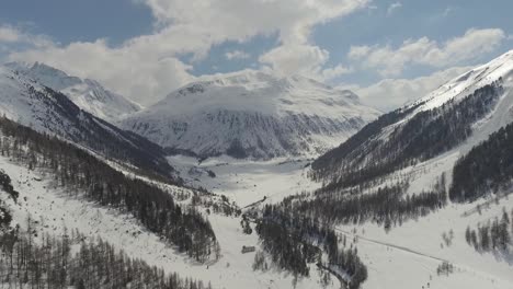 alpine valley with stream, road and individual houses between steep high mountains