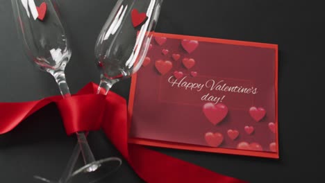 happy valentine's day text over champagne glasses with hearts and red ribbon